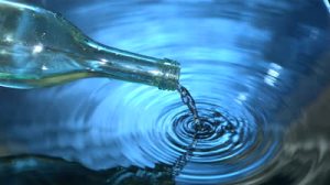 stock-footage-glass-bottle-pouring-water-into-blue-water-in-slow-motion